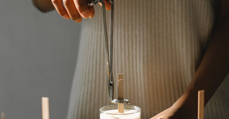 DIY Movements - Unrecognizable African American female standing at wooden table with candle and steel wick dipper in light room with sunlight