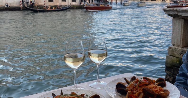Volunteer Tourism - Seafood and White Wine on a Restaurant Table by the Canal