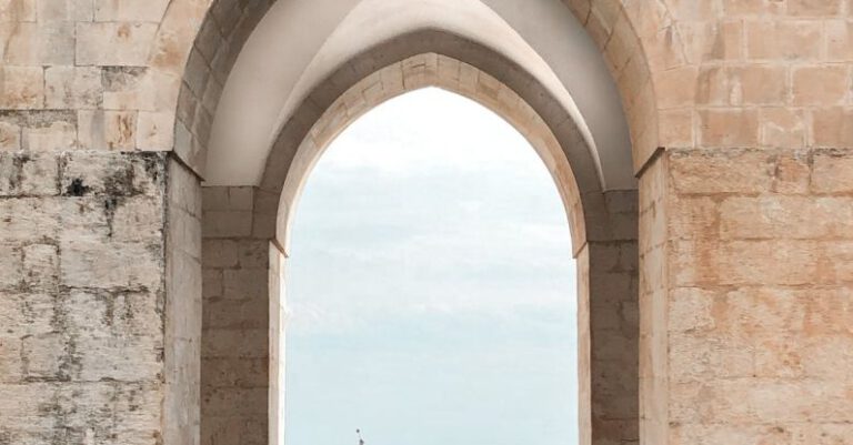 Space Tourism - Two People Sitting under an Arch and Looking at Sea
